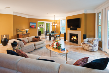 The living room of the Balays’ condominium has a fireplace with sleek granite surround, a generously proportioned flat-screen TV, a cozy cream-colored sectional couch, and plenty of natural light.